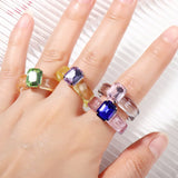 4 bagues plastiques portées sur la main d'une femme, deux sur le l'index, une sur le majeur et une sur l'annulaire.