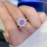 Bague pompadour avec moissanite rose et pétales en zircones portée sur le majeur d'une femme.