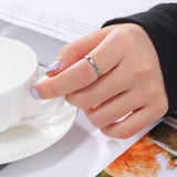 Main de femme portant une bague prénom argentée sur son majeur.