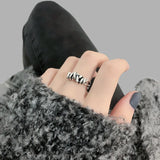 Bague réglable argentée portée sur le majeur d'une femme.