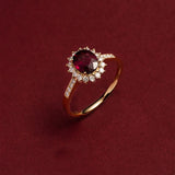 Bague rubis de couleur or, avec une pierre principale ovale et un halo de petits zircones.