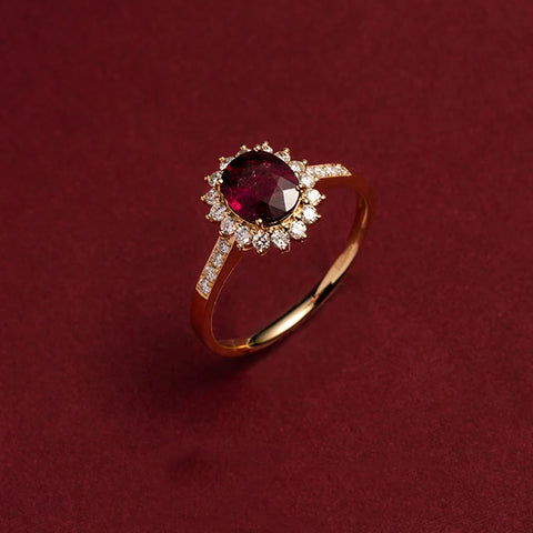 Bague rubis de couleur or, avec une pierre principale ovale et un halo de petits zircones.