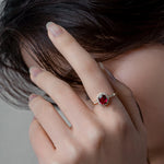Femme élégante portant une bague rubis au design ovale et serti de petites pierres claires.