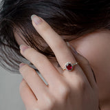 Femme élégante portant une bague rubis au design ovale et serti de petites pierres claires.