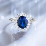 Bague saphir bleue avec des pierres blanches disposées comme des pétales.
