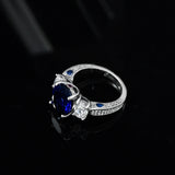 Bague saphir diamant avec un saphir bleu ovale et un anneau en argent serti de zircones.