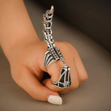 Bague scorpion avec la queue de scorpion pointant le ciel portée sur l'index d'une femme.