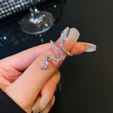 Main de femme portant une bague serpent de couleur argentée sur son pouce.