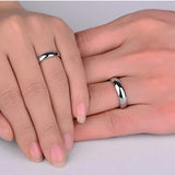 Deux bagues simples en titane argentée, une portée sur l'annulaire d'un homme et l'autre sur l'annulaire d'une femme.