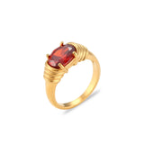 Bague tendance en acier et titane couleur dorée, avec une pierre rouge.