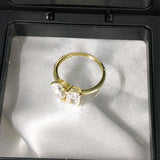 Bague toi et moi diamant doré posée dans un écrin blanc et noir.