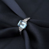 Bague topaze bleue avec un anneau en argent sterling 925 glissée sur un tissu foncé.