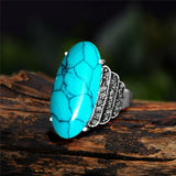Bague turquoise avec une pierre synthétique ovale et un anneau couleur argenté.