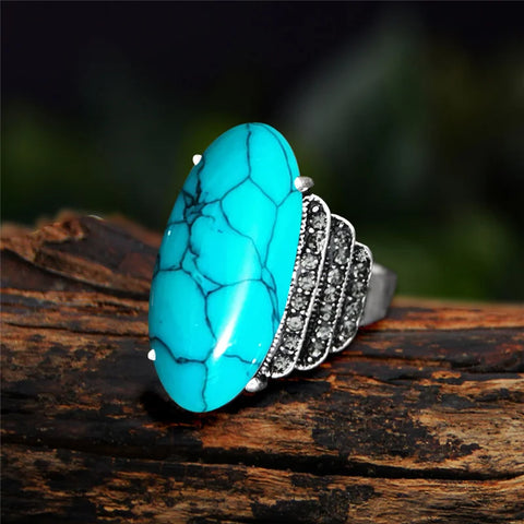 Bague turquoise avec une pierre synthétique ovale et un anneau couleur argenté.