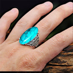 Main de femme portant une bague turquoise argentée sur son majeur.