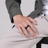 Main d'homme portant une bague vintage noire en acier sur le majeur.