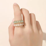 Deux bagues en perles portées sur l'index d'une femme, une rose et une verte.