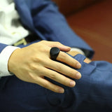 Main d'homme portant une bague personnalisée noire sur l'index.