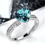 Bagues solitaires couleur argentée avec pierre bleue en forme de coeur et anneau pavé de zircones.