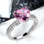 Bagues solitaires avec anneau argenté pavé de pierres et pierre rose en forme de coeur.
