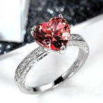 Bagues solitaires avec une pierre rouge en forme de coeur et anneau serti de petites pierres.