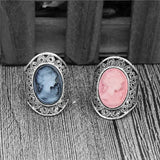 Deux camées bagues porsées sur une table, une avec une pierre bleue et une avec une pierre rose.