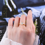 Bague solitaire dorée en argent 925 sur une jolie main de femme, sur le majeur.