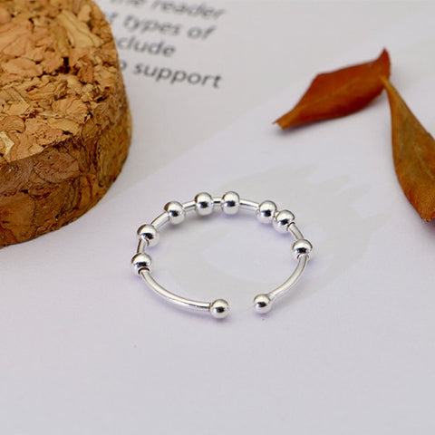 Bague anti-stress en argent à taille réglable avec huit billes pivotantes.