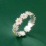 Bague marguerite couleur argent avec une chaîne de maguerite posée sur une table verte.
